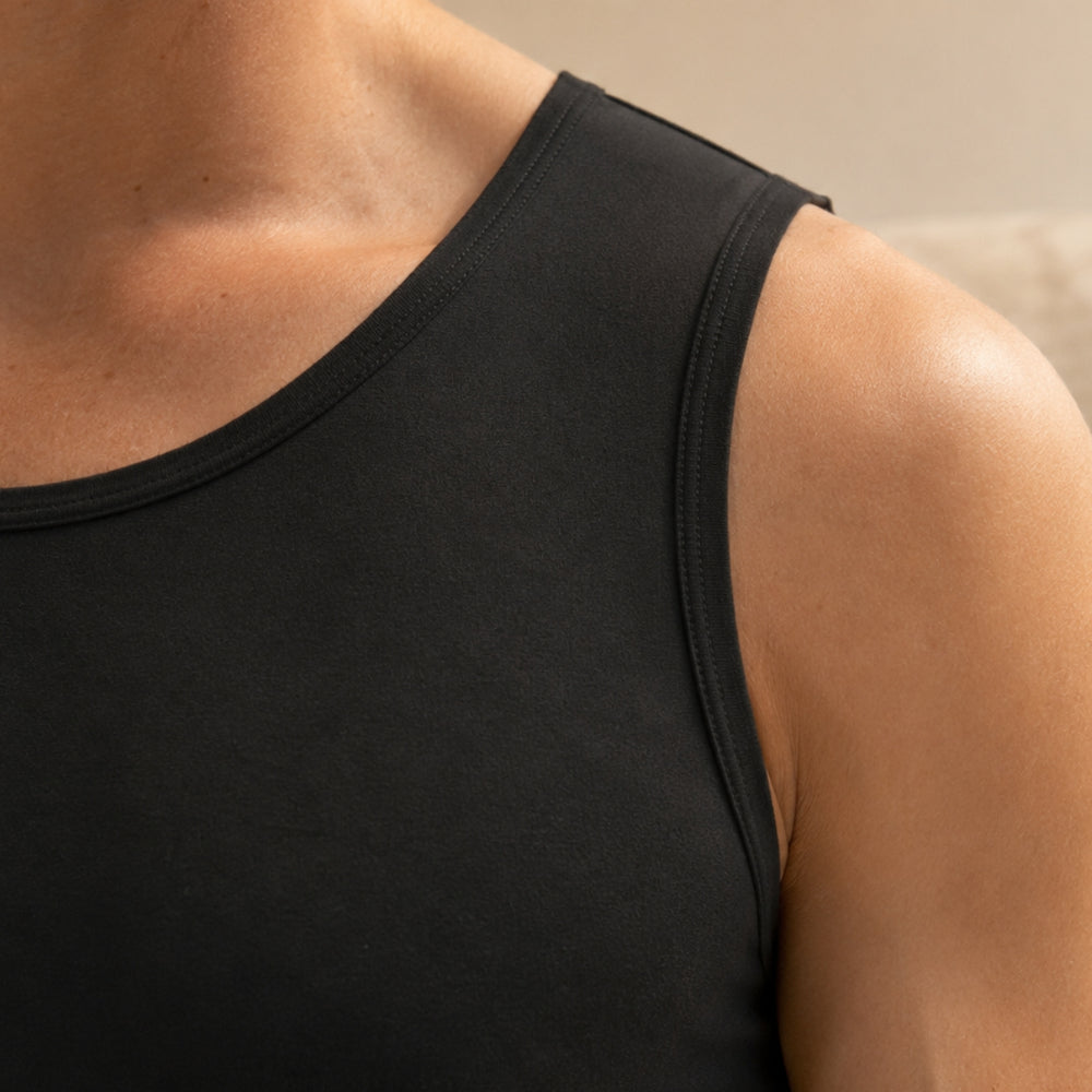 Détail de l'encolure du débardeur compressif Trame noir, porté à même la peau.